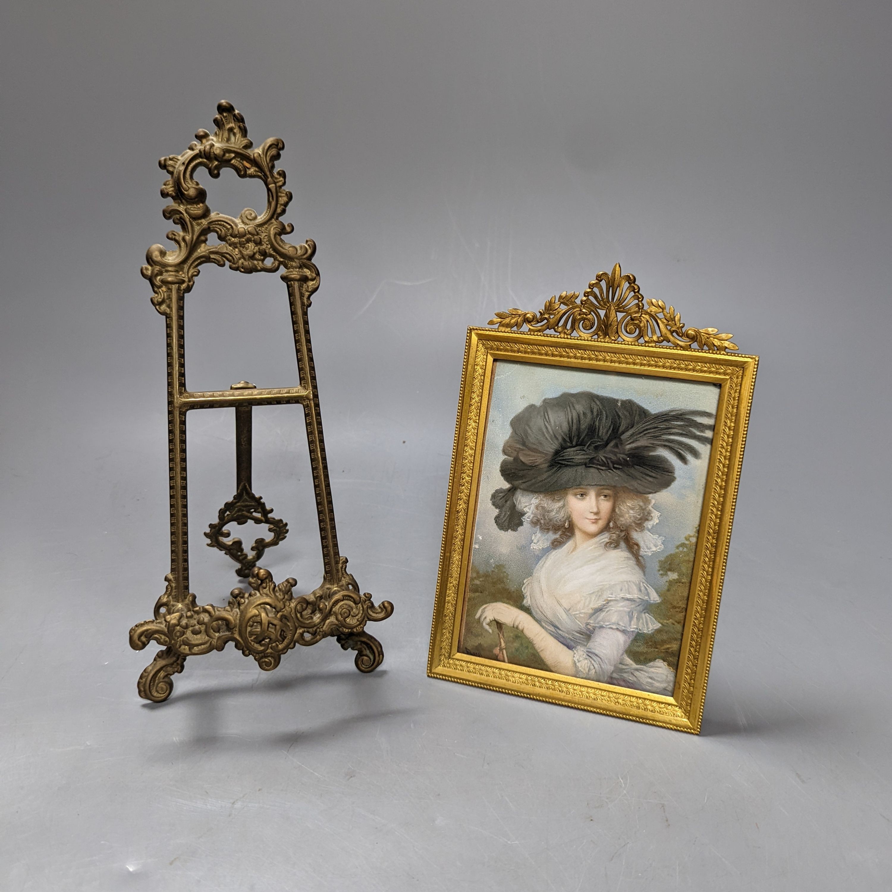 Victorian miniature print of a lady in a black feather hat in a gilt brass frame and a small brass easel, easel 25 cms high.
